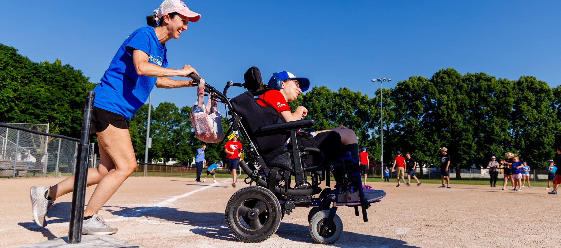 Young girl being push in wheelchair on baseball diamond